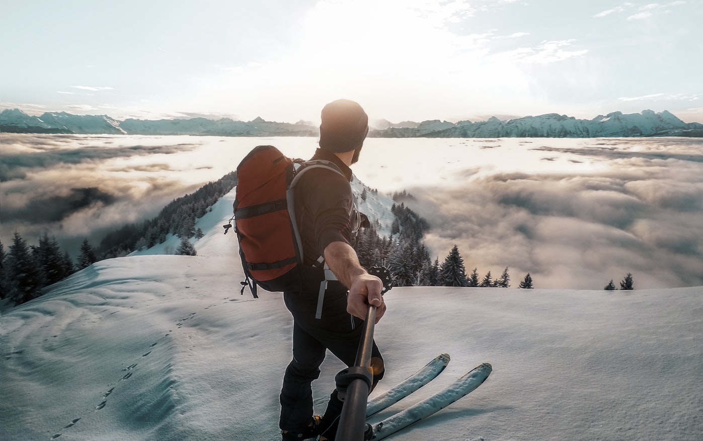 man on skis in the snow holding a selfie stick