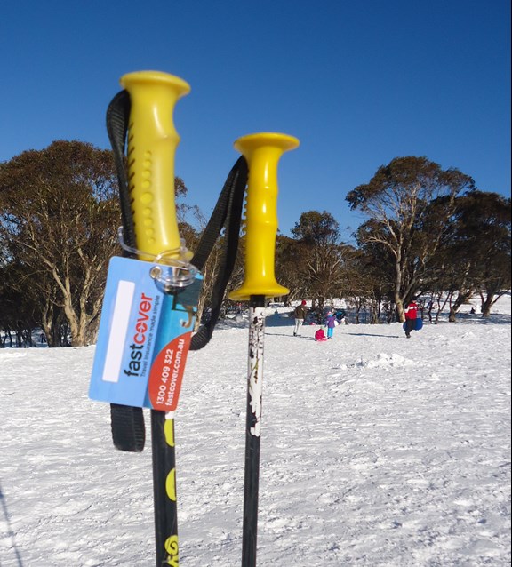 Yellow ski poles with Fast Cover luggage tag in the snow