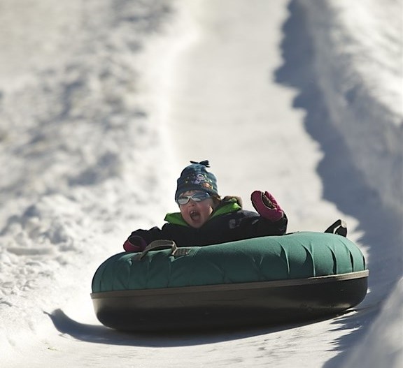 Boy having fun sliding down toboggan field at Selwyn Snow Resort holiday