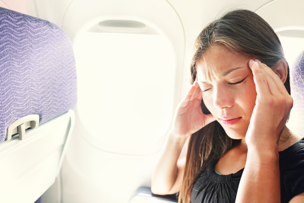 woman with travel sickness headache on plane