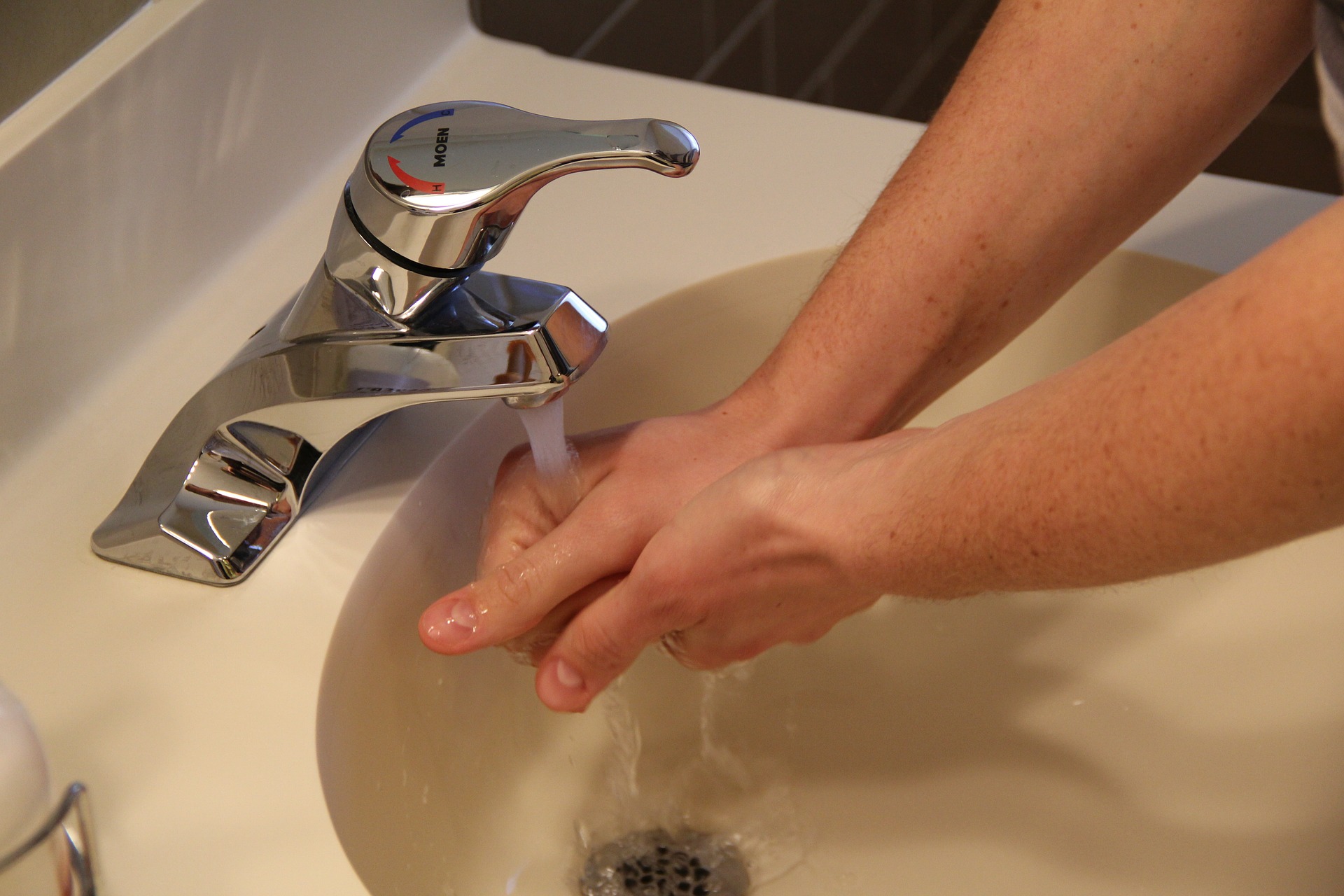 person washing hands in sink