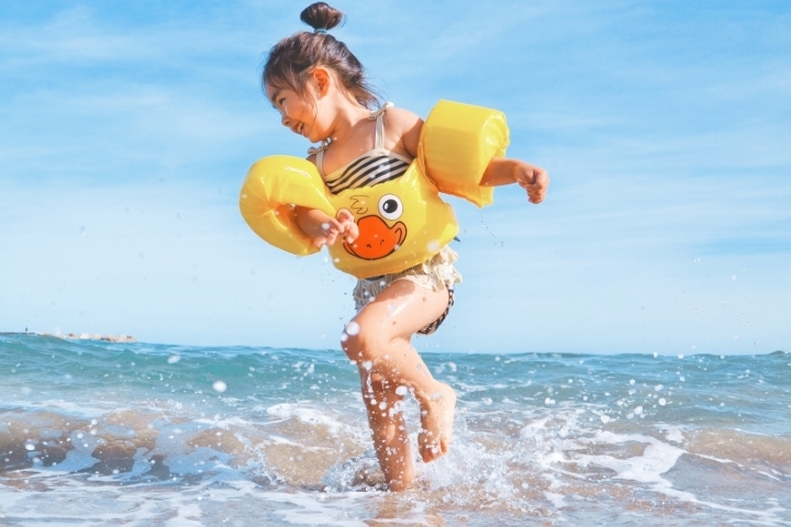 little girl wearing floaties on thai beach