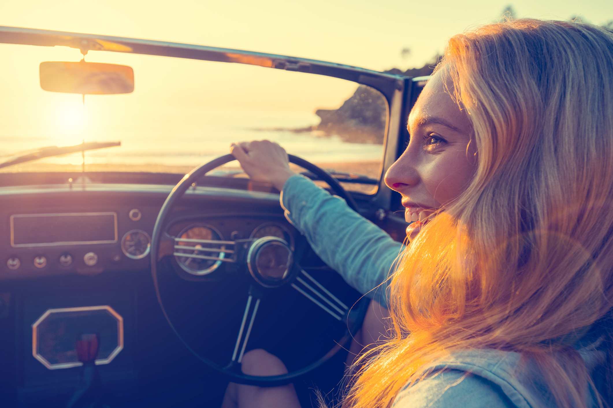 woman driving convertible at sunset
